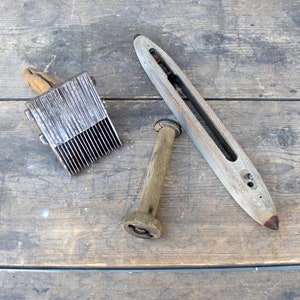 May include: Three wooden tools for weaving, including a shuttle, a bobbin, and a comb with metal teeth.