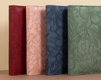 May include: Four leather-bound journals with floral embossed designs. The journals are in shades of red, pink, blue, and green.