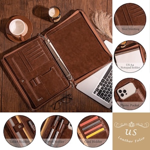 Pode incluir: Pasta de couro marrom com um fich&aacute;rio de argolas, v&aacute;rios bolsos e um bolso para telefone. A pasta est&aacute; aberta para revelar um porta-bloco de notas e um porta-tablet. A pasta est&aacute; sobre uma superf&iacute;cie de madeira.