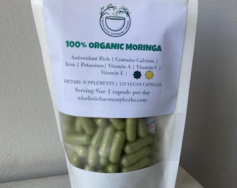 Puede incluir: Una bolsa blanca resellable con una etiqueta que dice "100% Moringa Orgánica" y enumera los beneficios nutricionales del suplemento. La bolsa contiene 120 cápsulas verdes de polvo de moringa.