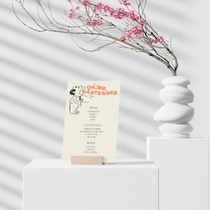 May include: A white card with a cartoon illustration of a person holding a glass of wine. The card has the text "Oh, Mr. Bartender" at the top and lists wine, cocktails, and beer options.
