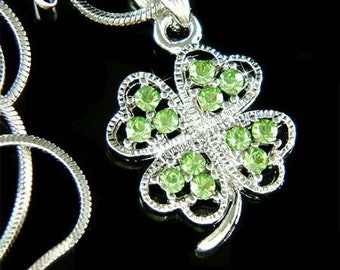 Puede incluir: Collar de plata con un colgante de trébol de cuatro hojas adornado con cristales de cristal verde.