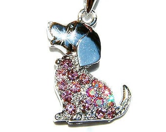 Può includere: Un ciondolo a forma di cane in cristallo rosa su una collana d'argento. Il cane è seduto con la testa inclinata e la lingua fuori. Il ciondolo è in metallo e ha una finitura lucida.