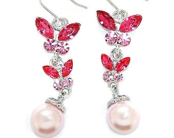 Peut inclure: Une paire de boucles d'oreilles pendantes avec des papillons en cristal rose et rouge et une perle rose au bas.