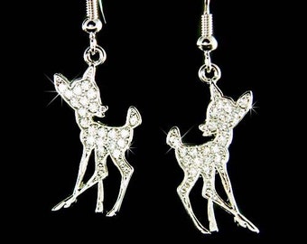 May include: Silver dangle earrings featuring a crystal-encrusted deer silhouette.