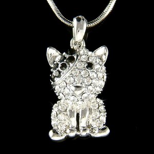 May include: A silver necklace with a crystal-encrusted cat pendant. The cat is sitting with its paws together and has black and white crystals.