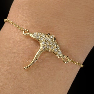 May include: A gold chain bracelet with a clear crystal-encrusted stingray charm. The charm is detailed and has a black eye.