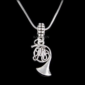 May include: Silver necklace with a French horn charm. The charm is detailed and has a silver chain.