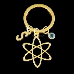 Peut inclure: Porte-cl&eacute;s dor&eacute; avec un charme lettre 'S', un petit charme en cristal bleu et un charme atome dor&eacute;.