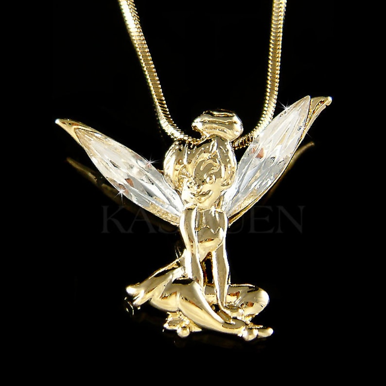 Puede incluir: Un collar con colgante dorado que presenta un dise&ntilde;o de hada con alas claras y brillantes. El hada est&aacute; en posici&oacute;n sentada, con intrincados detalles en la orfebrer&iacute;a dorada. El collar tiene una delicada cadena dorada, ideal como accesorio caprichoso.