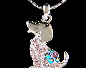 Può includere: Collana in argento con un ciondolo a forma di cucciolo tempestato di cristalli. Il cucciolo è seduto con la testa inclinata verso l'alto e ha cristalli rosa e blu.
