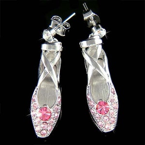 Può includere: Un paio di orecchini a forma di ballerina d'argento con accenti di cristallo rosa.