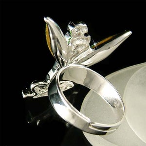 May include: Silver ring featuring a detailed butterfly design with yellow and green accents. The butterfly's wings are spread out and the ring is adjustable.