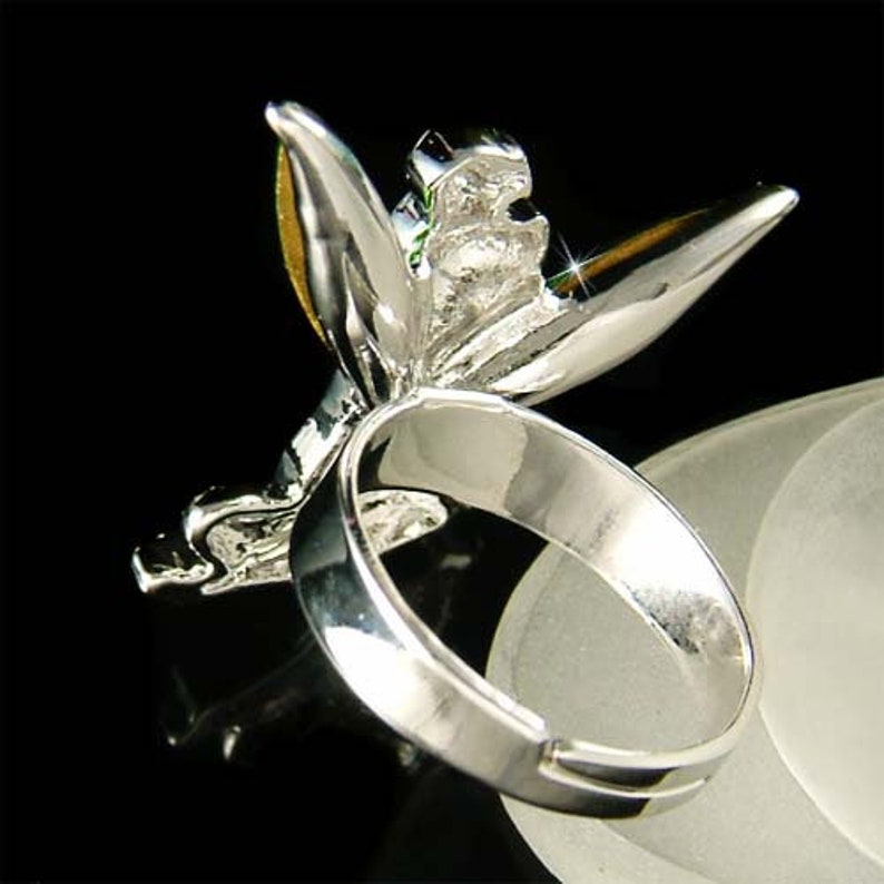 May include: Silver ring featuring a detailed butterfly design with yellow and green accents. The butterfly's wings are spread out and the ring is adjustable.