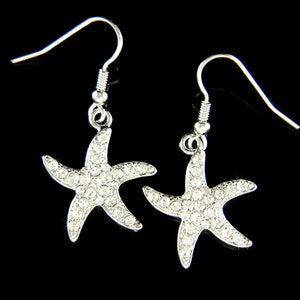 May include: A pair of silver dangle earrings featuring a sparkling starfish design with clear rhinestones.