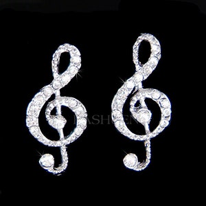 May include: A pair of silver tone earrings shaped like treble clefs, each decorated with clear rhinestones.