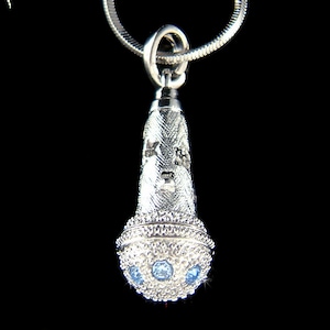 May include: Silver microphone pendant necklace with blue crystal accents.