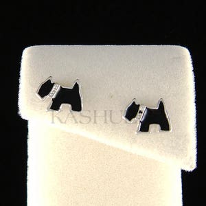 May include: A pair of silver stud earrings featuring a black enamel silhouette of a Scottish Terrier with a single diamond on the collar.