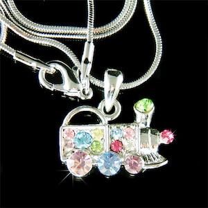 May include: A silver chain necklace with a colorful crystal train pendant. The train is decorated with pink, blue, green, and yellow crystals.