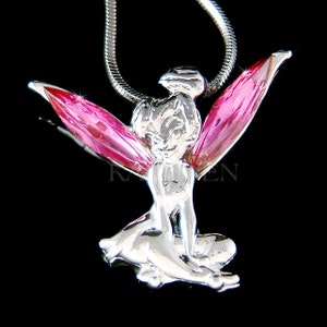 May include: A silver-toned pendant necklace featuring a Tinkerbell figurine with pink crystal wings. The pendant is on a silver chain.