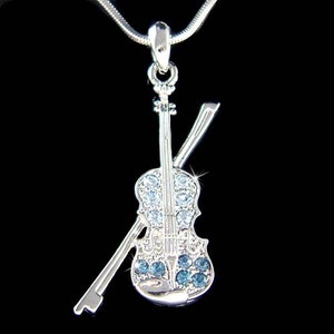 May include: Silver-tone violin pendant necklace with blue crystal accents. The violin is set against a black background.