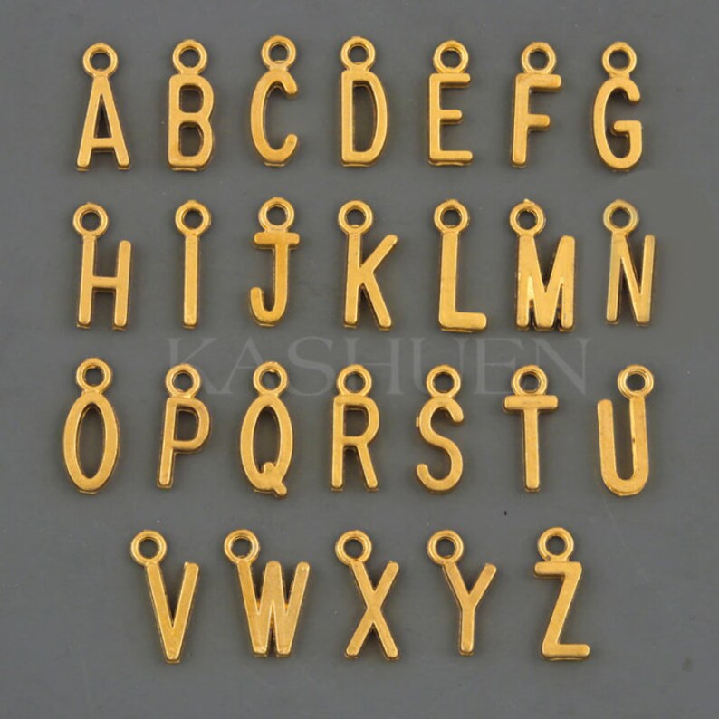 Peut inclure: Breloques en m&eacute;tal dor&eacute; en forme de lettres de l'alphabet avec une boucle en haut. Les lettres sont dispos&eacute;es en ordre alphab&eacute;tique de A &agrave; Z.