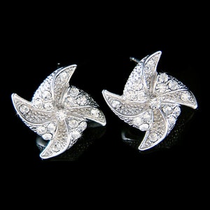 May include: A pair of silver earrings with a pinwheel design, each earring is encrusted with clear rhinestones.