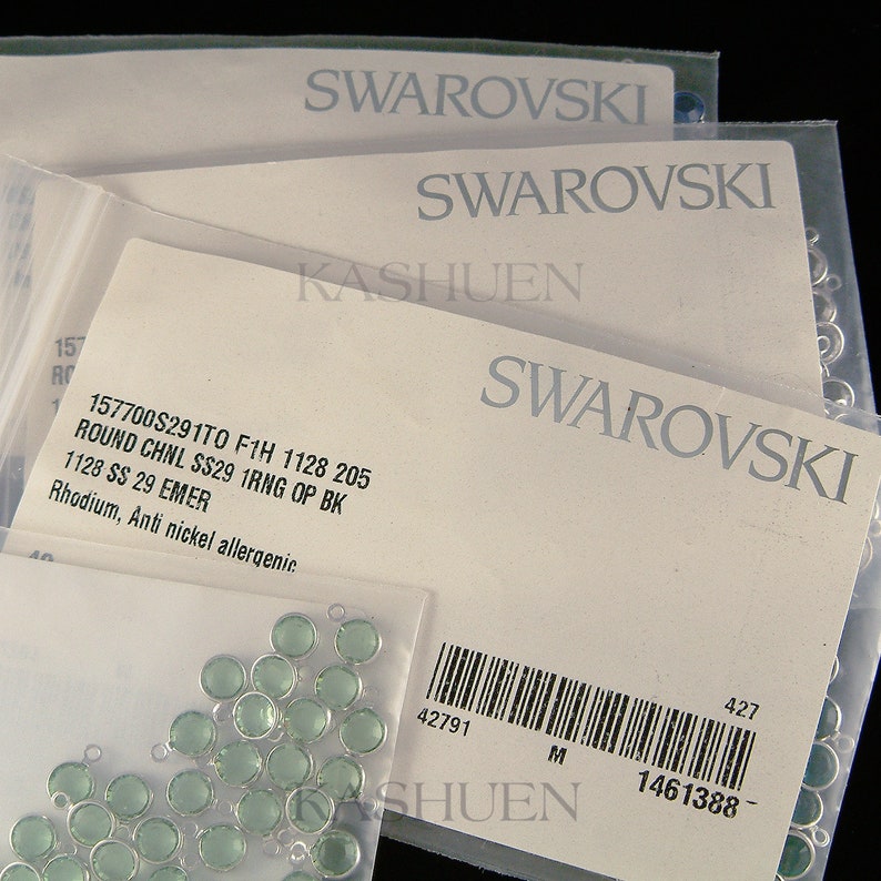 Peut inclure: Gros plan sur un paquet de perles de cristal vert clair avec des boucles argent&eacute;es. L'emballage est &eacute;tiquet&eacute; avec le texte "Swarovski" et le code produit "157700S291T0 F1H 1128 205".