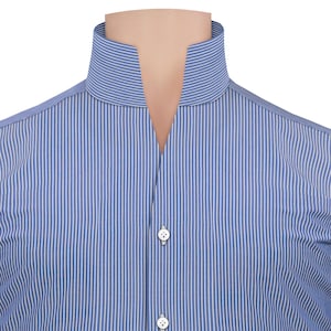 May include: A close-up of a blue and white striped shirt. The shirt has a high, open collar and two white buttons. The fabric is vertically striped, giving a classic, tailored appearance. The shirt is displayed on a mannequin.