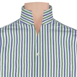 Puede incluir: Primer plano de una camisa a rayas con un diseño de cuello único. La camisa presenta rayas verticales en blanco, azul y verde. Se ve un solo botón blanco en el escote. La camisa está hecha de una tela ligera.