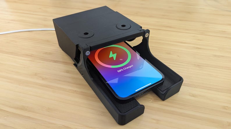 May include: A black wireless charging station with a smartphone inside. The phone screen shows a charging indicator with the text "89% Charged".