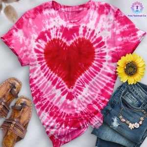 Peut inclure: Un t-shirt tie-dye rose et blanc avec un grand cœur rouge au centre. Le t-shirt est fait d'un tissu doux et confortable et est parfait pour une tenue décontractée.