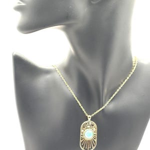 May include: A gold chain necklace with a pendant featuring a turquoise blue stone surrounded by a sunburst design.