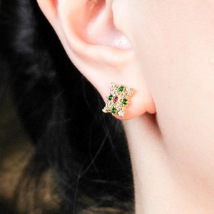 May include: Gold stud earrings with a cluster of white, green and red gemstones.