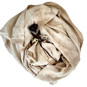 May include: A beige fabric scarf with a brown, dried rose tucked inside. The fabric has a tie-dye pattern.