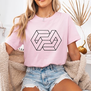 May include: A pink t-shirt with a black geometric design. The design is a 3D optical illusion of a cube.