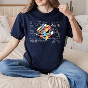 a woman sitting on a bed holding a rubik cube