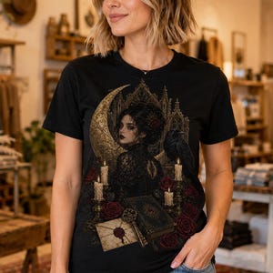 May include: A black t-shirt featuring a graphic print of a person in lace clothing, a large crescent moon, a raven, lit candles, red roses, a sealed envelope, and an ornate book. The design is set against a dark, intricate architectural backdrop.