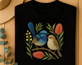 Puede incluir: Camiseta negra de manga larga con un diseño bordado de dos pájaros posados en una rama, rodeados de hojas y flores. Un pájaro es azul, el otro es marrón. Las flores son rojas y amarillas.