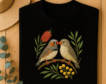 Puede incluir: Sudadera negra de cuello redondo con un diseño bordado de dos pájaros posados en una rama. Los pájaros tienen plumas grises y marrones, con una flor roja y hojas verdes. El diseño está centrado en la parte delantera de la prenda.