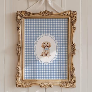 Pode incluir: Uma impressão emoldurada com uma ilustração em aquarela de um cão dourado usando uma gravata borboleta azul, em um fundo xadrez azul e branco. A moldura dourada ornamentada está pendurada em uma parede de madeira branca.