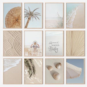 May include: A set of twelve framed art prints with a coastal theme. The prints depict a beach umbrella, palm trees, sand, ocean waves, and seashells in neutral colours. The phrase "Good Vibes Only" is written in the sand in one print.