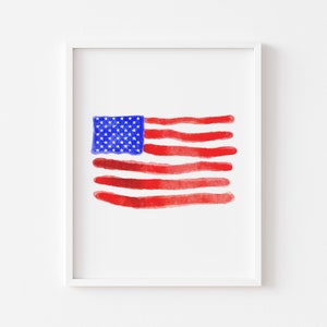 Puede incluir: Una pintura de acuarela de la bandera estadounidense en rojo, blanco y azul. La bandera está pintada en un estilo simple y abstracto.