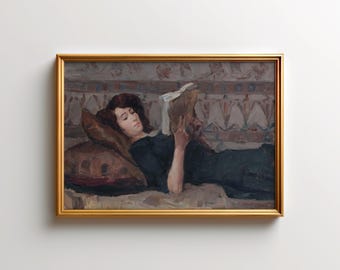 May include: A framed painting depicts a woman reclining on a patterned surface, engrossed in a book. She wears a dark dress and rests on a brown pillow. The artwork is enclosed in a gold-colored frame, creating a classic aesthetic.