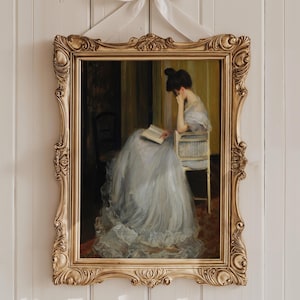 May include: An ornate, gold-framed painting depicting a woman in a flowing blue dress seated and reading a book. The artwork is mounted on a white wooden wall and tied with a white ribbon.