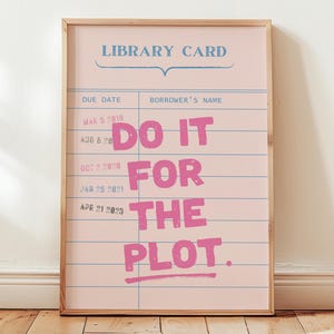 May include: A framed pink print with the words "DO IT FOR THE PLOT" in large pink letters. The print is designed to look like a library card, with lines for due dates and borrower's name. The frame is made of light wood.