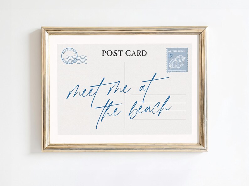 May include: Framed postcard print with the words "meet me at the beach" in blue script. The postcard design includes a postage stamp and post office markings in blue, set against a cream background.