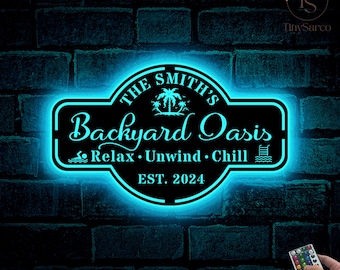 May include: A black and white personalized sign with a blue neon glow around it. The sign says "The Smith's Backyard Oasis Relax. Unwind. Chill Est. 2024".