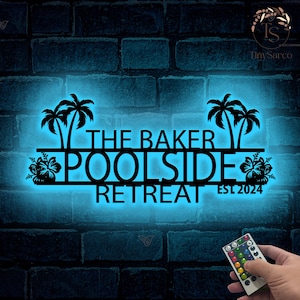 Può includere: Cartello in metallo nero con il testo "The Baker Poolside Retreat Est 2024" e due palme su entrambi i lati. Il cartello è illuminato da una luce blu.