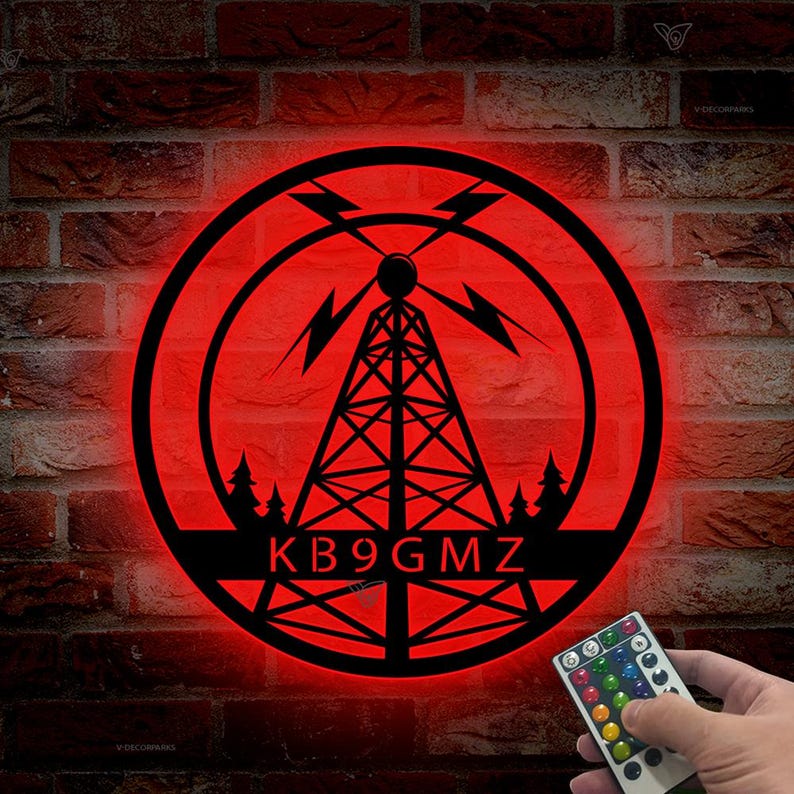 May include: A red illuminated round sign with a black silhouette of a radio tower and trees. The text "KB9GMZ" is displayed below the tower. A remote control with color changing LED lights is shown in the bottom right corner.